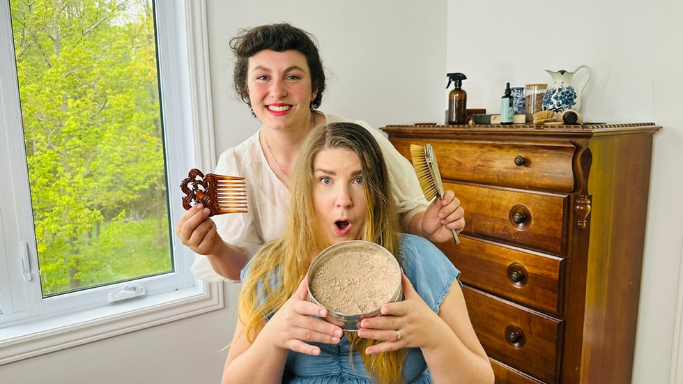 Two women indoors, one holding a metal bowl filled with rhassoul clay powder while the other holds wooden combs, surrounded by natural hair products on a wooden dresser.