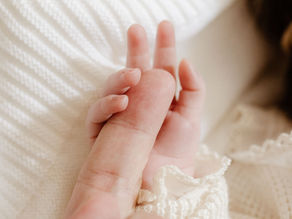 Baby grasping an adults finger
