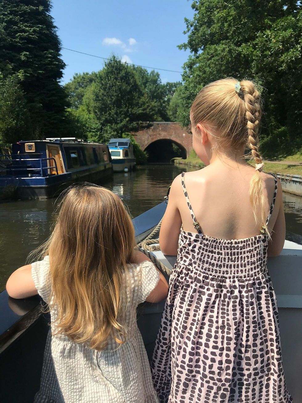 Two yound girls on a canal barge wearing summer dresses