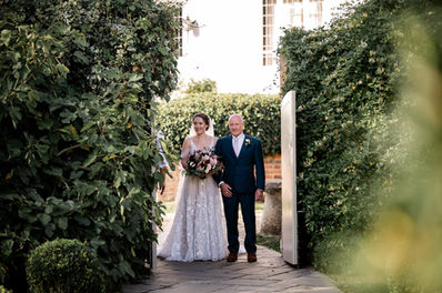 Bride and proud dad walking down garden aisle at Houchins wedding