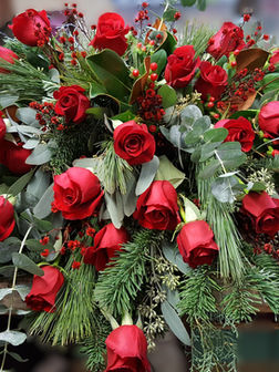 Funeral casket spray floral arrangement with red roses with greenery