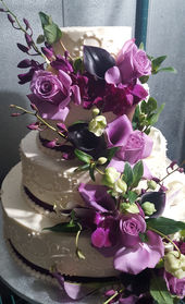 Wedding cake with roses, orchids, mini calla lilies and other flowers in shades of green and purple. November fall wedding
