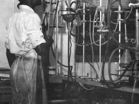 A young African-American man wearing protective gear stares at a wall of tubes and funnels