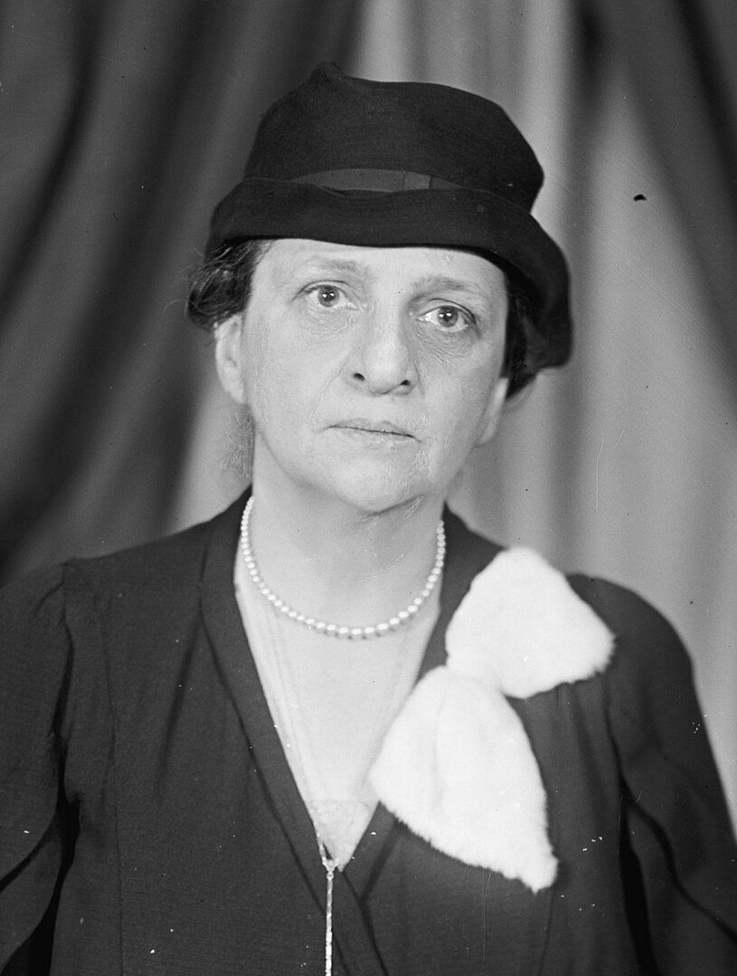 A middle-aged woman with dark hair and eyes stares straight at the camera; portrait of Frances Perkins