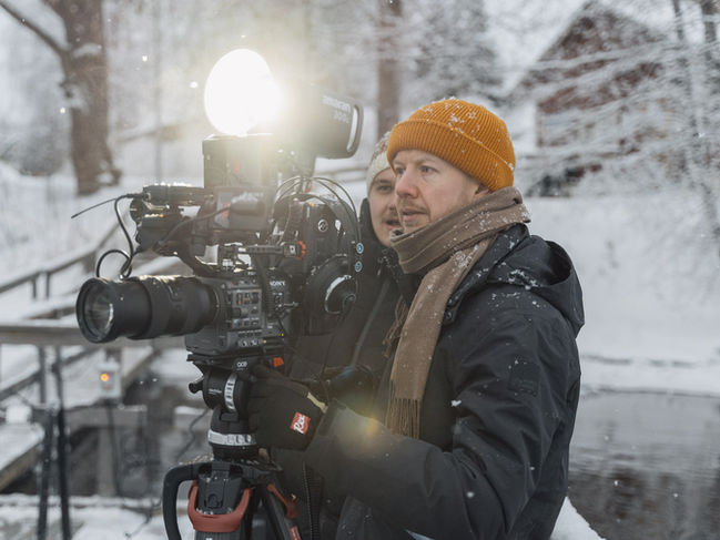 Videokuvaaja kuvaamassa ulkolokaatiossa talvisessa ympäristössä ammattikameralla osana yritysvideotuotantoa.