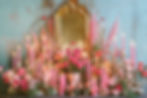 lit pink candles and roses surrounding a gold mirror on an altar