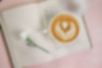coffee art of a heart sitting in the middle of an open book with a white flower and pink background