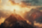 Man standing on top of a mountain with the rising sun