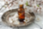 bottle of essential oil on a silver platter with white flowers