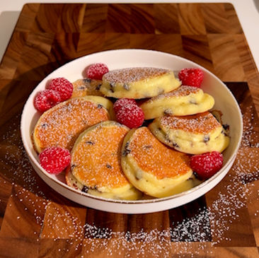 Un piatto di freschi e leggeri pancake magici alla ricotta senza farina, con lamponi 