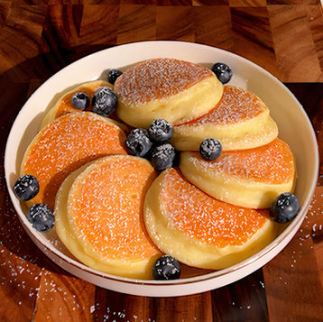 Un piatto di freschi e leggeri pancake magici al limone senza farina, con ricotta e mirtilli