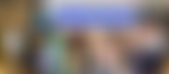 The RFIN team gathers for a group photo during a conference, showcasing their diverse and collaborative spirit against a backdrop of banners representing their mission and identity.