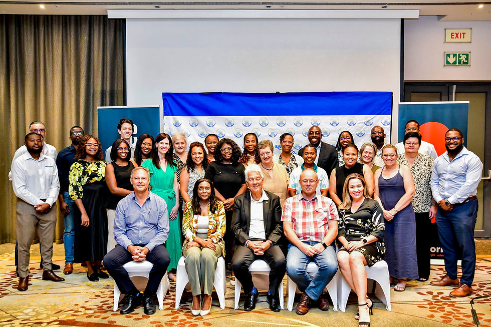 The RFIN team gathers for a group photo during a conference, showcasing their diverse and collaborative spirit against a backdrop of banners representing their mission and identity.