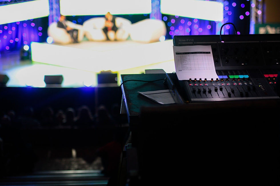 A close up of a mixing desk overlooking a TV studio