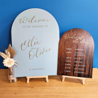 Hand painted and hand lettered wedding signs on a table in front of a blue wall