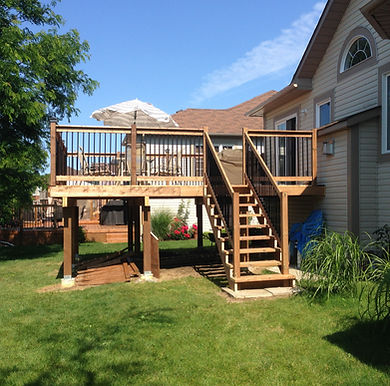Finished elevated deck with stairs, black railings, and patio umbrella – backyard upgrade project