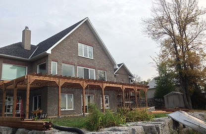 Large custom deck and pergola structure being built on a two-story home