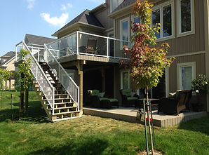 Raised deck with white glass railings and walkout below – multi-level deck construction
