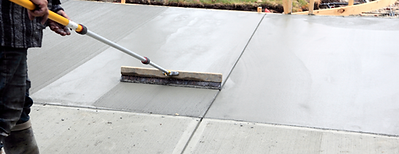 Freshly poured concrete driveway being smoothed – professional driveway installation in progress