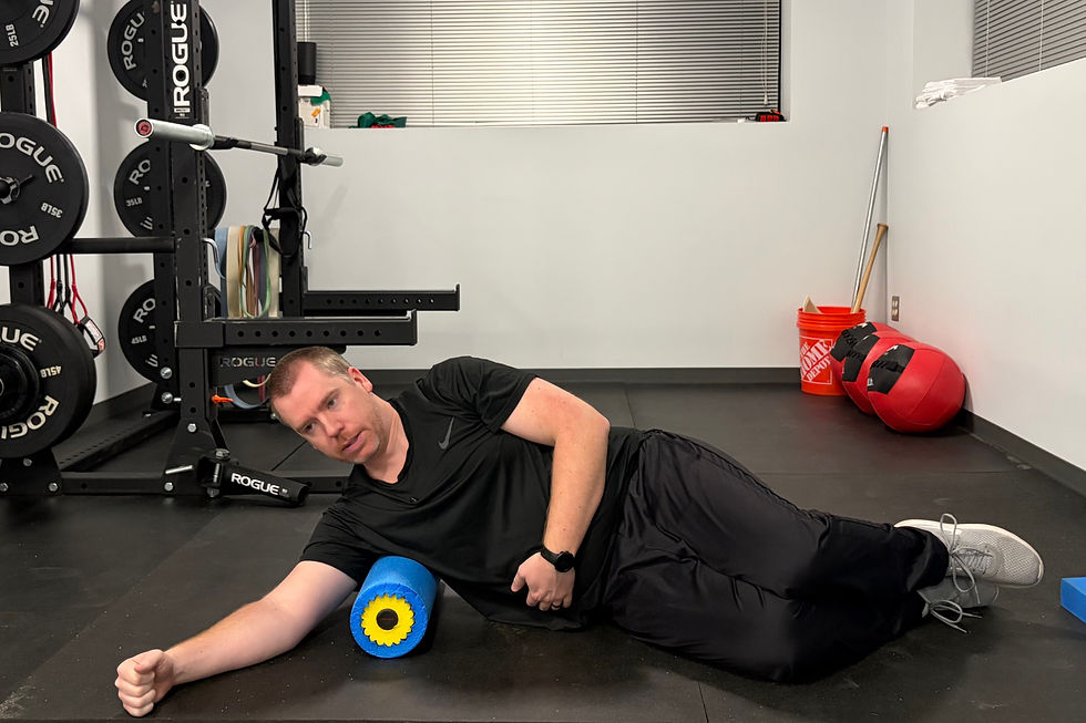 Dr. Danny Lehnert lays on his side with a foam roller between his lats and the floor.