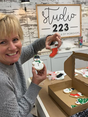 participant holding decorated holiday cookies at Studio 223 DIY workshop in Gilbert, AZ.
