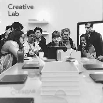 Katie sitting at a laptop surrounded by people as she demos a edtech tool.