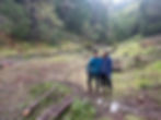 Jordan and Janeva of Upstream Ecology stand with their arms around each other in a forested landscape