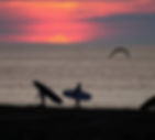 Surfers at Ocean City MD at sunset