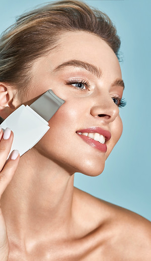 Ultrasonic facial peeling for a beautiful woman's face with ultrasonic scrubber, on blue b