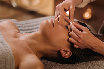 A cosmetologist girl does a facial and neck massage to a girl in the office for skin elast