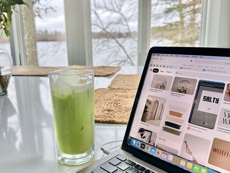 Computer on table with iced matcha drink.