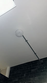 Smoke detector installation with metal conduit for fire safety compliance in a commercial shop.