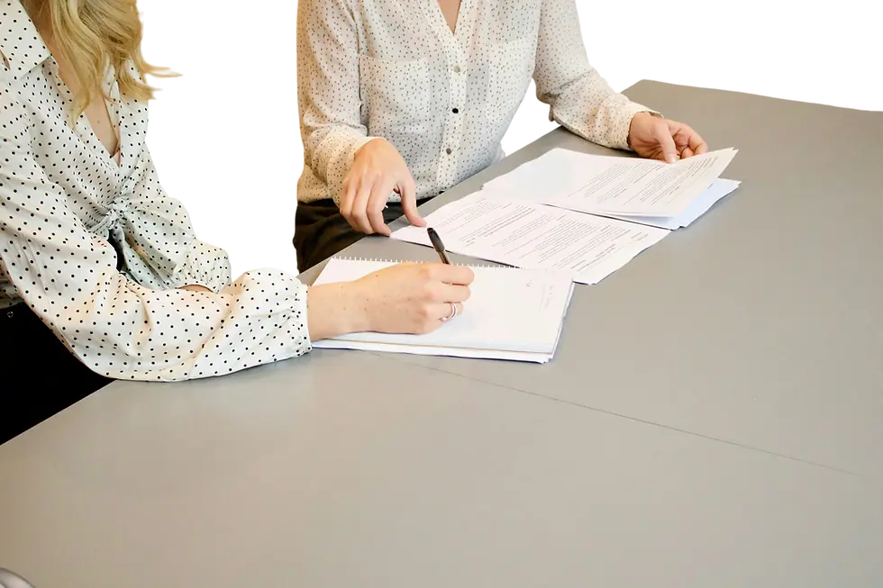 Studio photography of two people collaborating over documents at a table. The scene suggests a professional meeting or review.