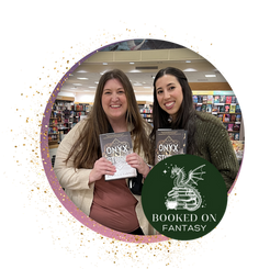 Podcast hosts Addison and Lorraine standing side by side in a bookstore holding copies of Onyx Storm. The Booked on Fantasy logo depicts a dragon on top of a book stack with a cauldron beside it.