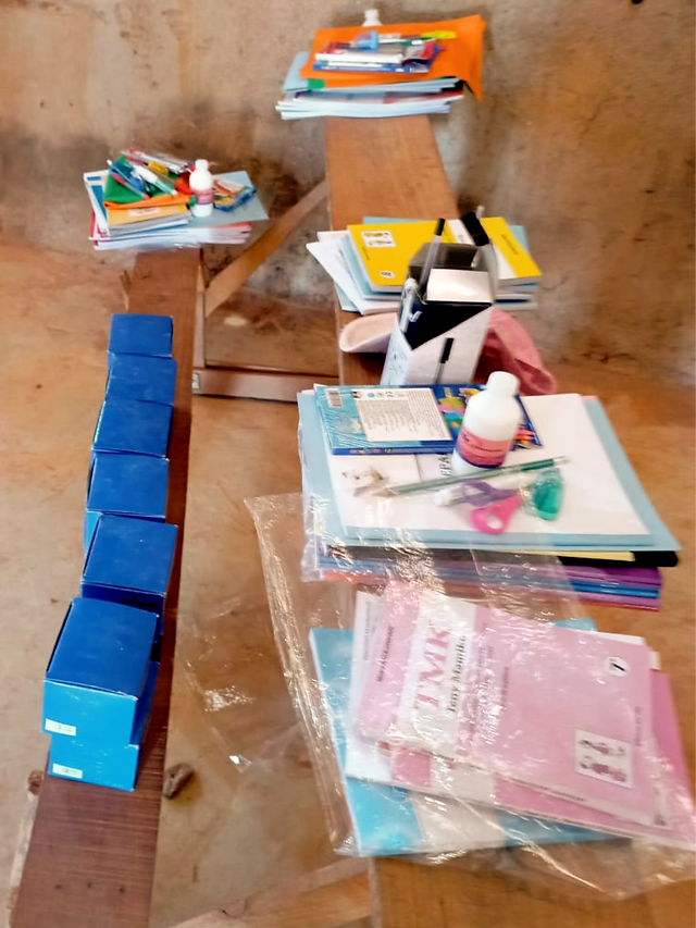 Educational materials and tools such as notebooks, crayons, and chalk, prepared for distribution