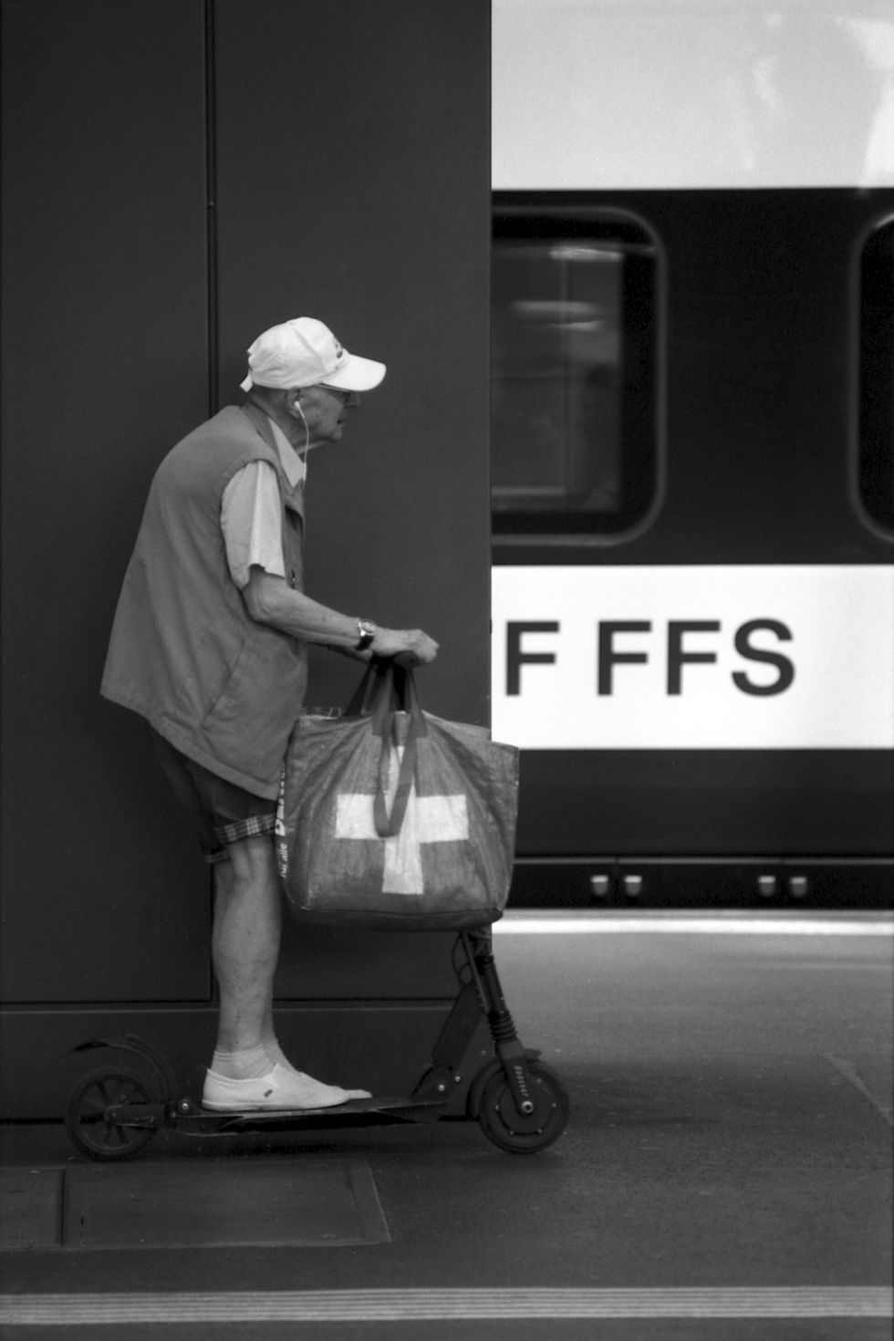 old man with bags riding a scooter at the central station in zuerich