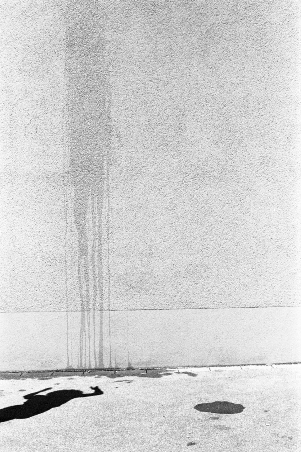 water splash on white wall with shadow of a person and stains on the floor