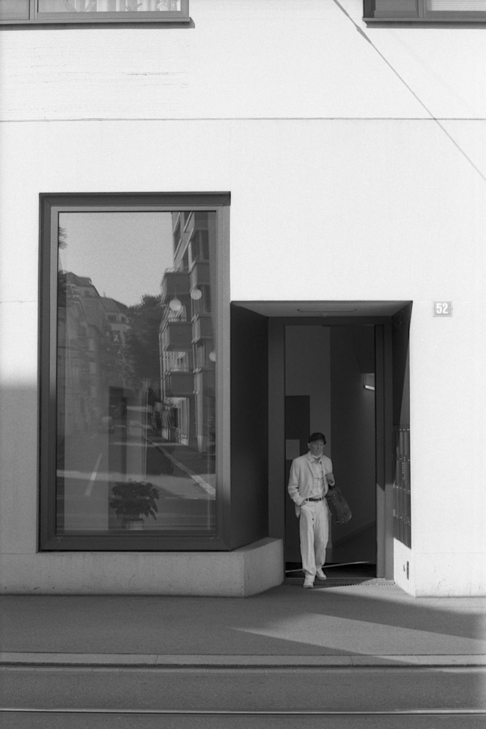 old man in white suit in front of a new building, high contrast black and white foto