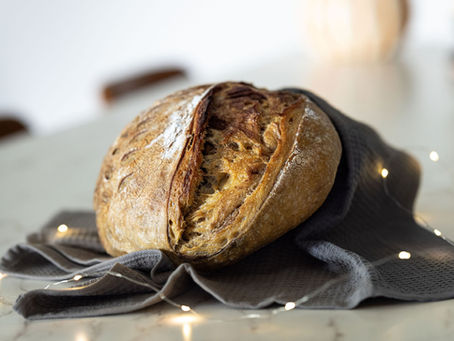 Close-up of golden, crusty sourdough loaf with open crumb on a linen cloth—featured image for a baking tips blog post.