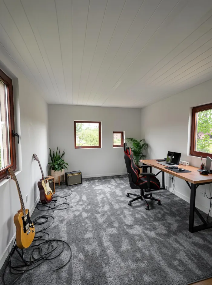 Render de interior con IA del estudio de jardín con el mobiliario principal colocado, incluyendo escritorio de trabajo, silla ergonómica, sofá, guitarras, taburetes y una pizarra que definen las zonas de trabajo y música.