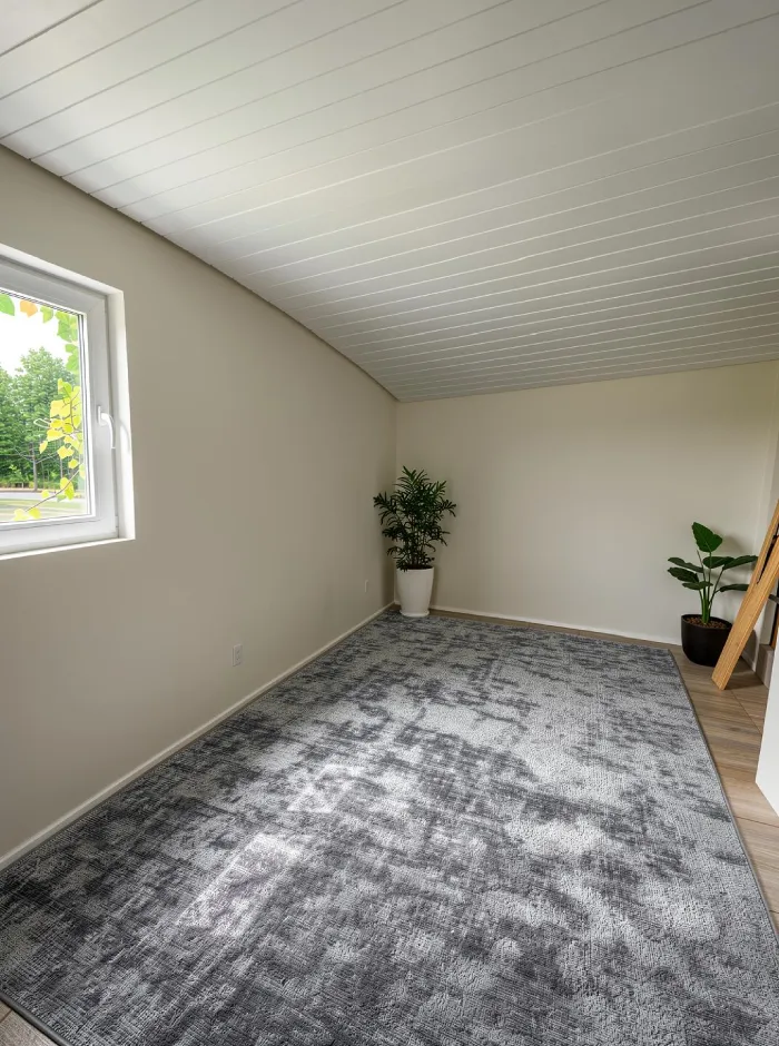 Concepto refinado del estudio de jardín que muestra el techo blanco más luminoso, las vigas oscuras rústicas y el suelo gris suave que crean una base más cálida y silenciosa para un estudio de música y trabajo.