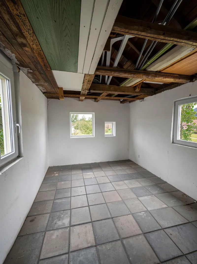 Trastero de jardín limpiado digitalmente con el módulo de Diseño de Interiores con IA de ArchiVinci, con paredes vacías, suelo de baldosas, ventanas y vigas de madera vistas tras eliminar todo el desorden y los muebles.