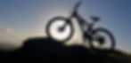 A silhouette of a mountain bike balanced on a rock