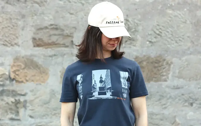 A woman wearing the Duke t-shirt, a blue-grey tee with a silhouette print in light grey of the Duke of Wellington in Glasgow with the cone on his head