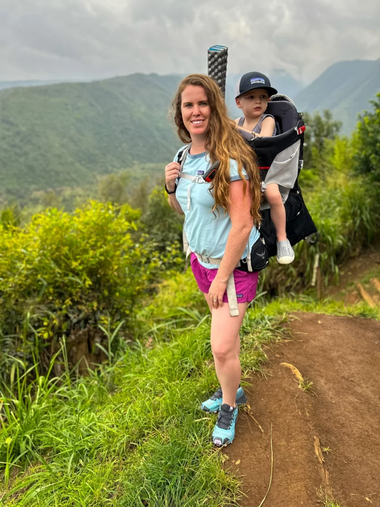 Adrianna hikes Polulu Valley with her son in a carrier on her back, one of the best family hikes on the Big Island.