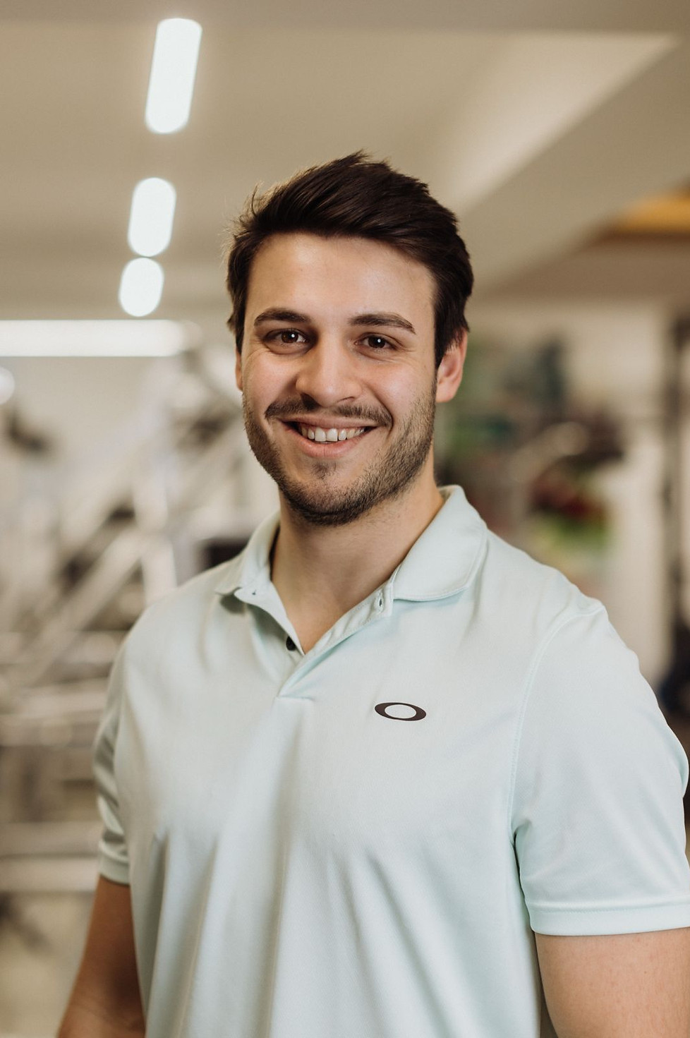 Freundlicher Physiotherapeut im modernen Fitnessraum und Therapieraum von Rebalance Physiotherapie und Osteopathie