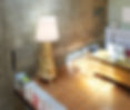 Lampe de sol dorée ornée dans bureau moderne murs béton et livres.
