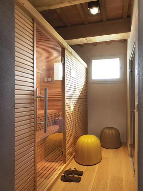 Sauna en bois moderne avec bancs, poufs jaunes et fenêtre lumineuse.