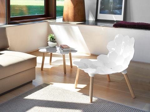Chaise blanche design floral, petite table moderne dans salon lumineux.