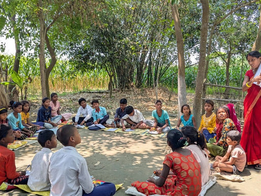 woman teaching children who are sitting in circle in outdoor setting